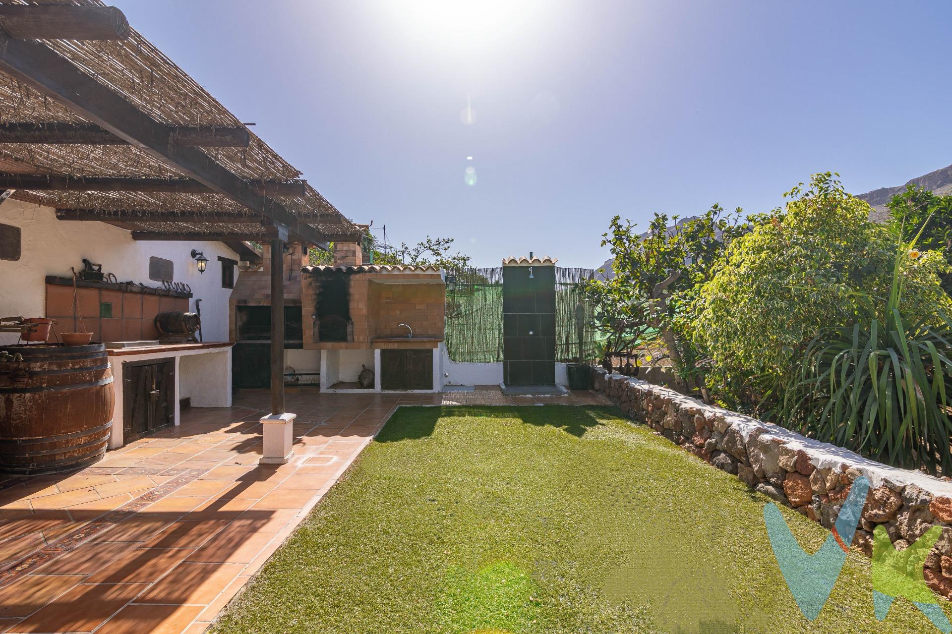 En armonía con la naturaleza: encantadora finca con terreno en Ayagaures:. El sur de Gran Canaria oculta impresionantes paraísos naturales, como el Barranco de Ayagaures. Excursionistas y senderistas aprecian esta zona. La carretera serpentea a lo largo de vegetación típica canaria y casas tradicionales, rodeada por las imponentes montañas, hasta el embalse de Ayagaures. En medio de este impresionante paisaje, bordeado de cactus, palmeras, dragos y pinos canarios, se encuentra esta bonita finca en venta. Situada junto a la carretera, se llega a la parcela vallada (aprox. 727 m2). La finca desprende un encanto muy especial. El porche en la entrada impresiona con materiales naturales por todos lados. Es un lugar donde se sentirá como en casa. Bajo del techo de una pérgola de madera, hay una terraza con rincones diseñados con mucho amor y acogedoras zonas con muebles rústicos, que invitan a desconectarse del mundo. Una bonita zona de barbacoa con parrilla y horno de ladrillo ofrece un lugar maravilloso para pasar tiempo con la familia y los amigos. La finca cumple, lo que promete. También el interior representa el encantador estilo rústico.                                                                                                        . El salón (con aire acondicionado y calefacción) le da la bienvenida con una bonita cocina rústica y una chimenea. Tragaluces en el techo inclinado proporcionan luz natural. Esta zona acogedora invita a tumbarse en el sofá junto a la chimenea, disfrutando de tranquilidad. Hay otra cocina independiente y equipada a su disposición. Un bonito dormitorio doble promete dulces sueños. El cuarto de baño con ducha continúa el diseña rústico. En las habitaciones impresionan decorativas vigas de madera que embellecen los techos inclinados. Las paredes están decoradas con Lajas, una típica piedra natural. La propiedad encanta por su sencillez en combinación con elementos naturales y colores marrones y tierra, que transmitan mucha armonía. Incluyendo la terraza, tiene aproximadamente 107 m2 construidos a su disposición. . Además, en el exterior, pequeños pasillos llevan a la zona plantada. Usted encuentra árboles frutales, plantas exóticas y suculentas. Como nuevo propietario, aquí usted podría cultivar sus propias plantas, árboles, frutas y verduras. ¿No es una idea tentadora?. Ayagaures forma parte del municipio turístico de San Bartolomé de Tirajana. El pintoresco paisaje está rodeado por el impresionante macizo montañoso. En invierno, el barranco se convierte en un paraíso verde. Alrededor encontrará encantadores restaurantes (incluido un restaurante cueva enfrente), enclavados en este impresionante paisaje natural. . En aprox. 20 minutos en coche usted llega al sur turístico, así como al mar y a las playas de Playa del Inglés, Maspalomas y Meloneras. El Palmitos Park y el moderno centro comercial El Tablero también están a unos 20 minutos en coche. El embalse de Ayagaures está a 5 minutos a pie. Este tranquilo oasis puede ofrecer al nuevo propietario un hogar lleno de calidez en armonía con la naturaleza. Aproveche esta oportunidad y póngase en contacto con nosotros. El precio no incluye impuestos y gastos de la compraventa: Impuesto de Transmisiones Patrimoniales (6,5%), honorarios de Notario, Registro de la Propiedad y gestoría. La oferta se sujeta a errores, cambios de precio, omisión y/o retirada del mercado sin aviso previo.
